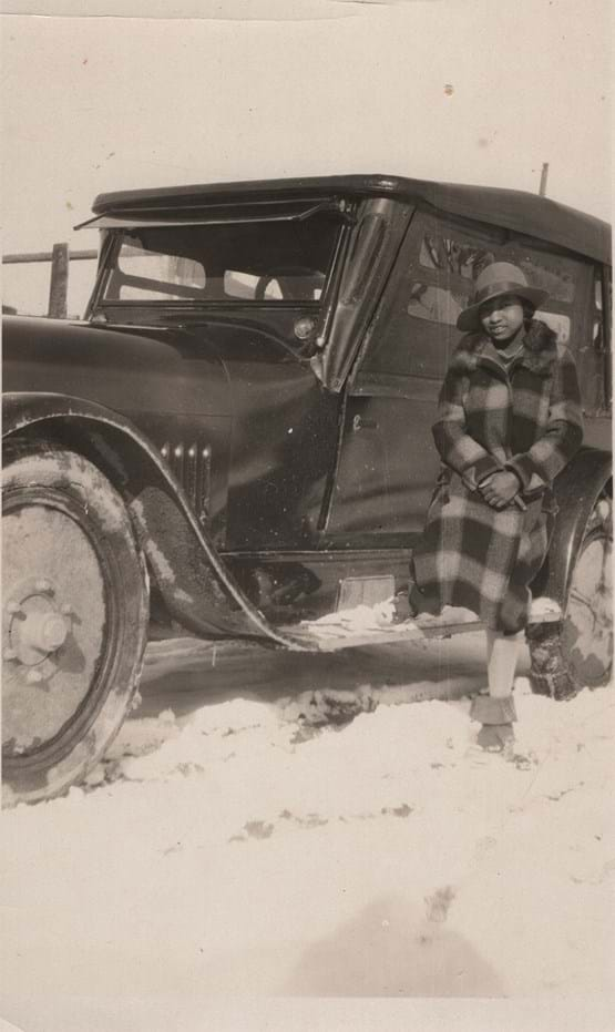 Erma Hayman leans against car in the snow.